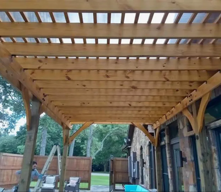 Cedar pergola with clear polycarbonate roof panels seen from below, built by Forged Fence & Deck in Pearland, TX